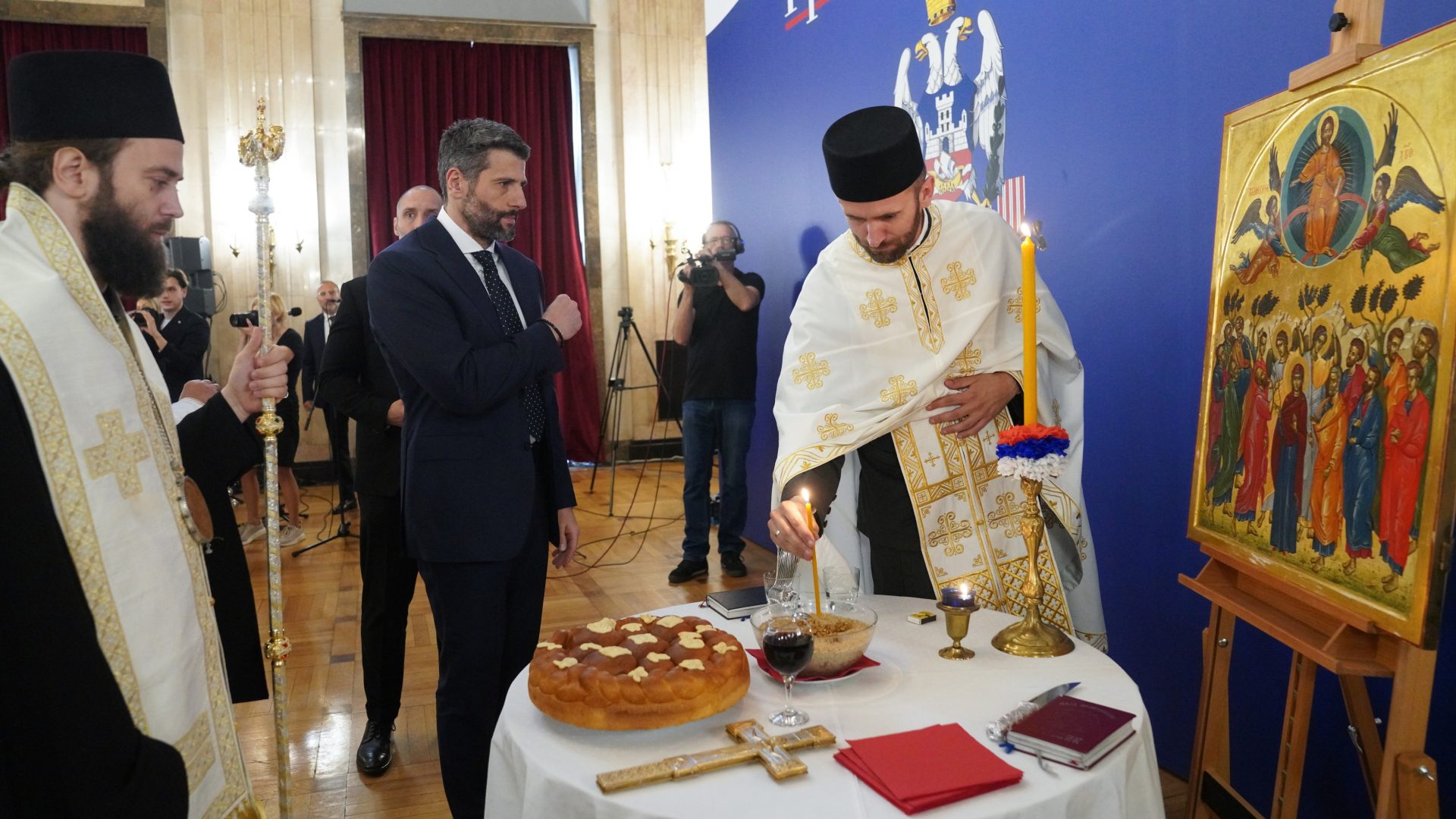 Александар Шапић и свештеник се припремају за сечење славског колача