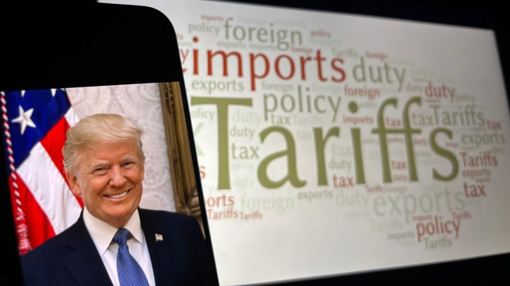 Фотографија Доналда Трампа на мобилном телефону, док је у позадини банер са исписаним речима: тарифе, царине, извоз, увоз